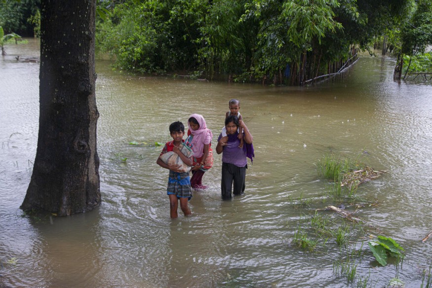 Villagers wade through floodwater in Morigaon district of Assam. (Image: AP)